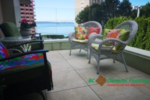 BCOF logo overlaying image of 12"x12" porcelain pedestal paver deck tiles on finished condo patio with furniture, overlooking the water