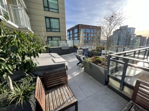 roof top terrace with grey porcelain pavers, planters, hot tub and outdoor kitchen