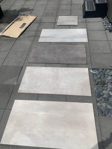 Porcelain paver laid out as samples on old deck surface