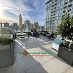 BCOF logo overlaying image of Rooftop terrace with outdoor kitchen and hot tub finished with porcelain pedestal pavers in grey